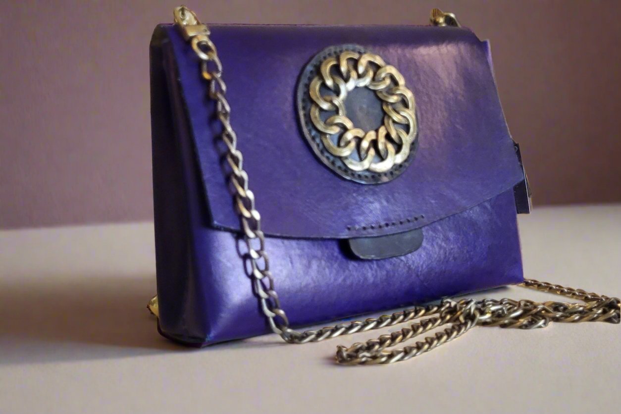 Blue purse with black pocket and burnished gold accents and curb chain strap.