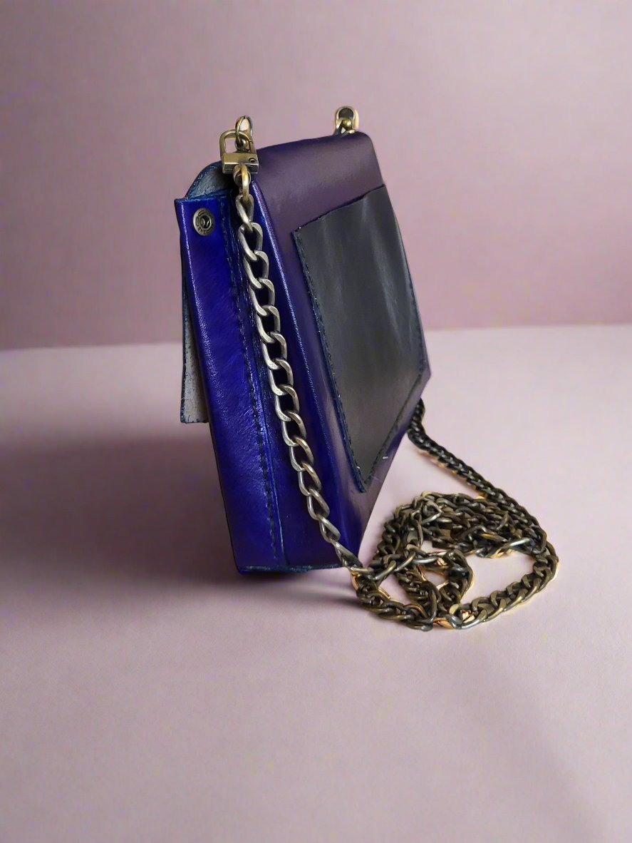 Blue purse with black pocket and burnished gold accents and curb chain strap.