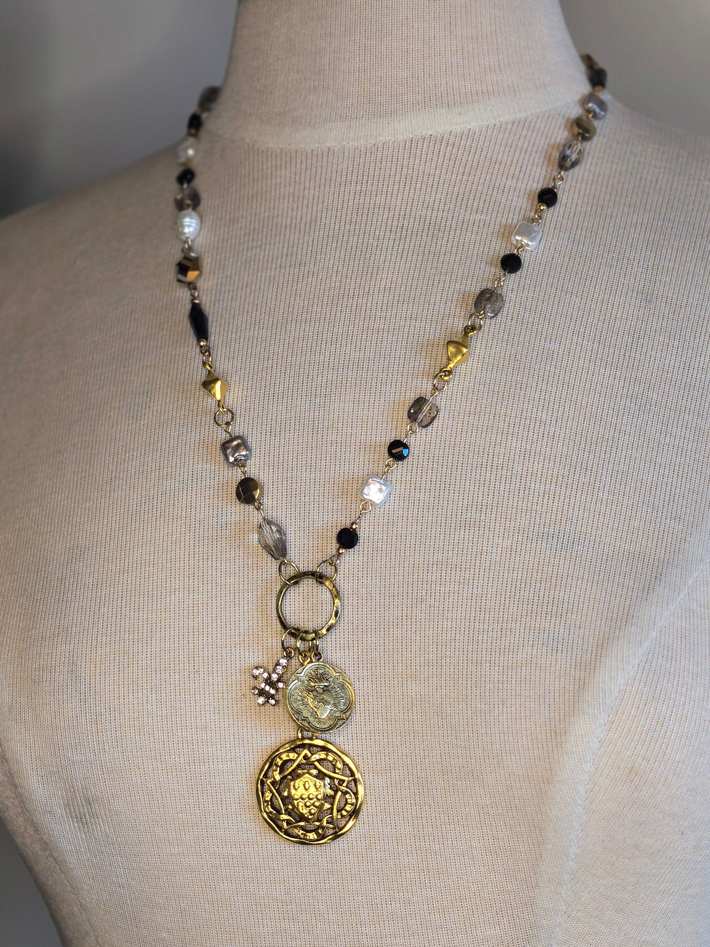 Necklace with decorative pendants on a mannequin bust against a neutral background