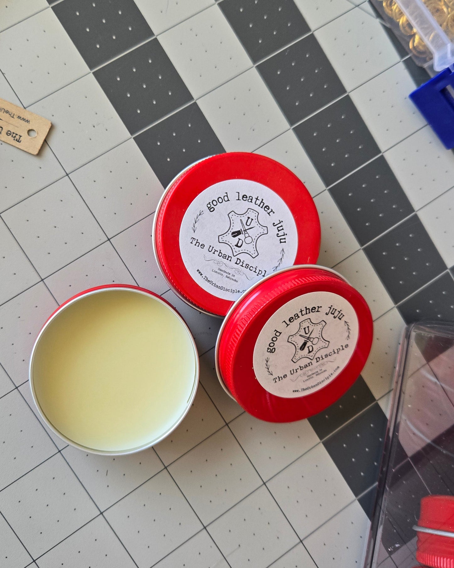 Two red containers with white lids on a checkered surface