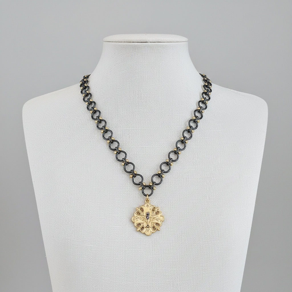 Necklace with a gold pendant on a mannequin against a neutral background