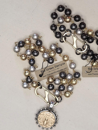 Matte Gold Queen Bee Coin in antique silver bezel on 22 inch tri-color pearl necklace.