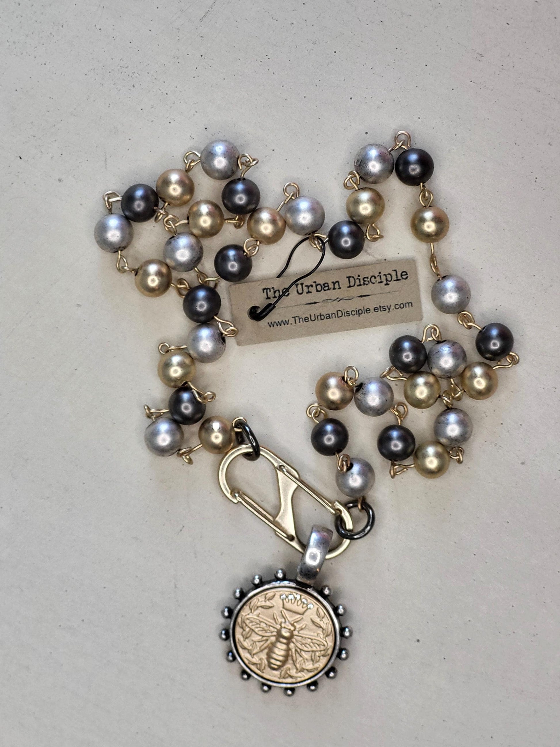 Matte Gold Queen Bee Coin in antique silver bezel on 22 inch tri-color pearl necklace.