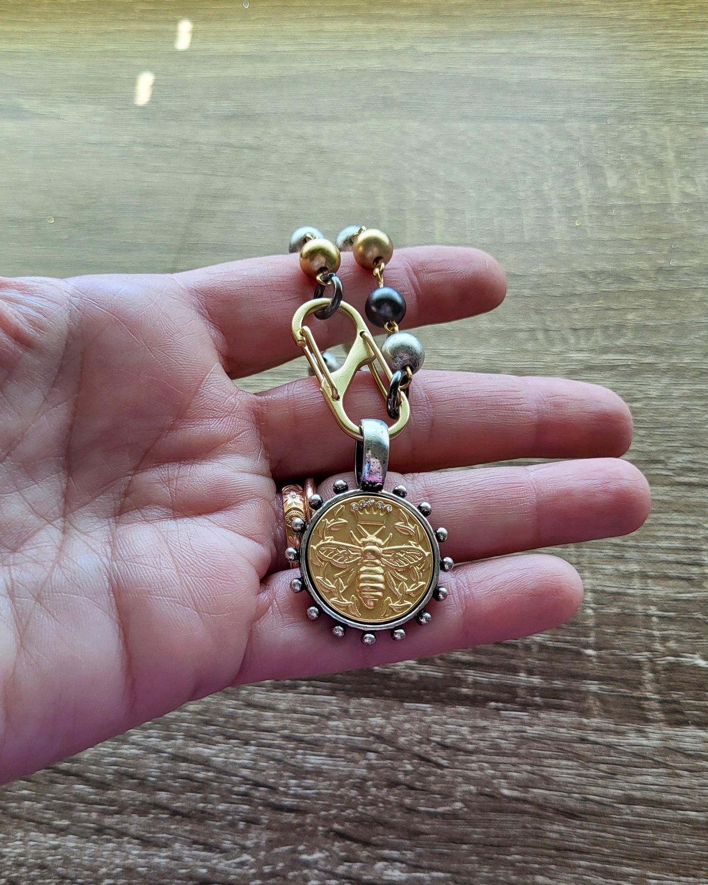 Matte Gold Queen Bee Coin in antique silver bezel on 22 inch tri-color pearl necklace.