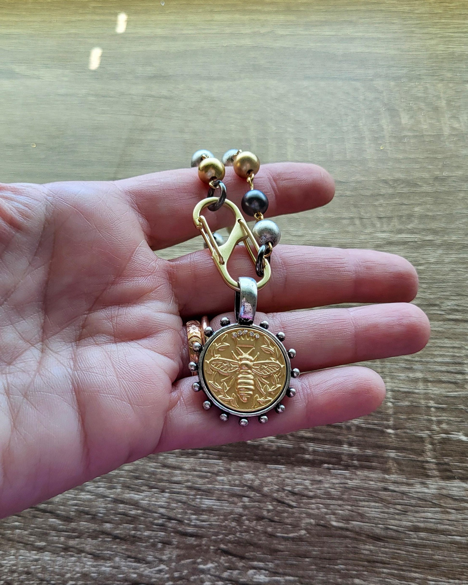 Matte Gold Queen Bee Coin in antique silver bezel on 22 inch tri-color pearl necklace.