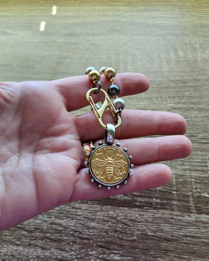 Matte Gold Queen Bee Coin in antique silver bezel on 22 inch tri-color pearl necklace.