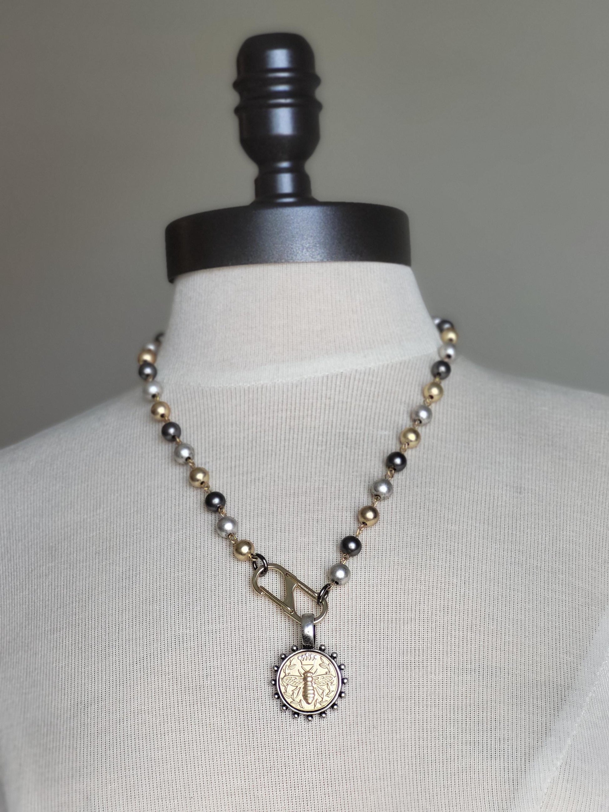 Matte Gold Queen Bee Coin in antique silver bezel on 22 inch tri-color pearl necklace.