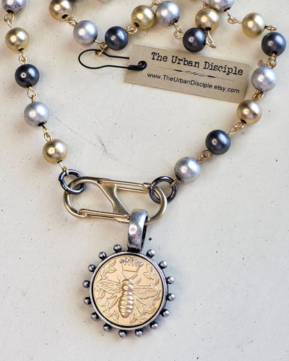 Matte Gold Queen Bee Coin in antique silver bezel on 22 inch tri-color pearl necklace.