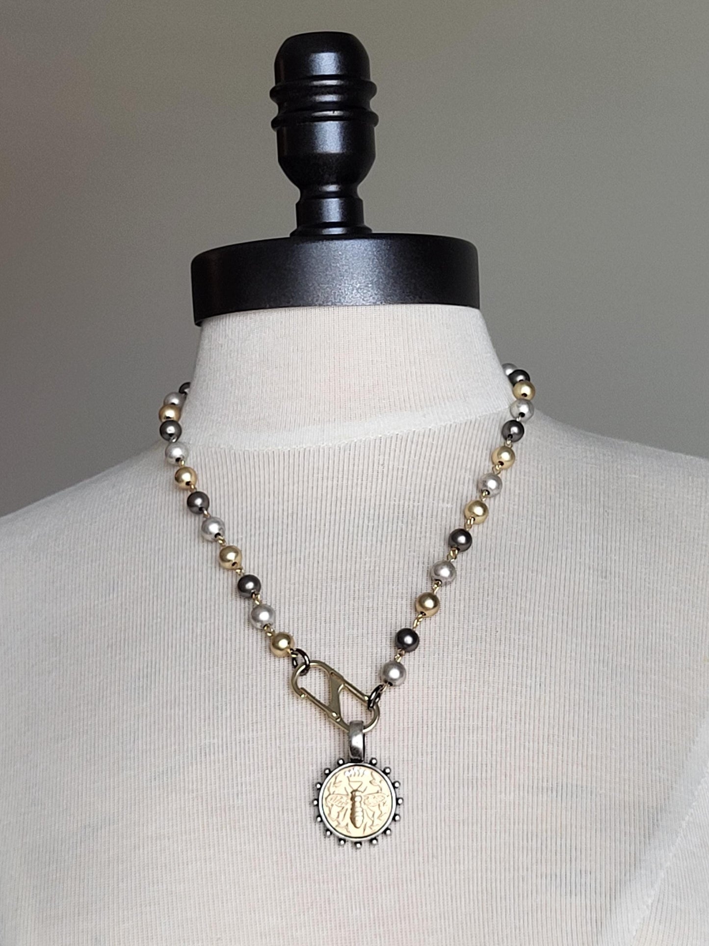 Matte Gold Queen Bee Coin in antique silver bezel on 22 inch tri-color pearl necklace.