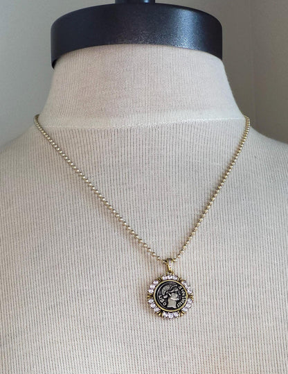 small mixed metal Greek coin pendant on gold ball chain.